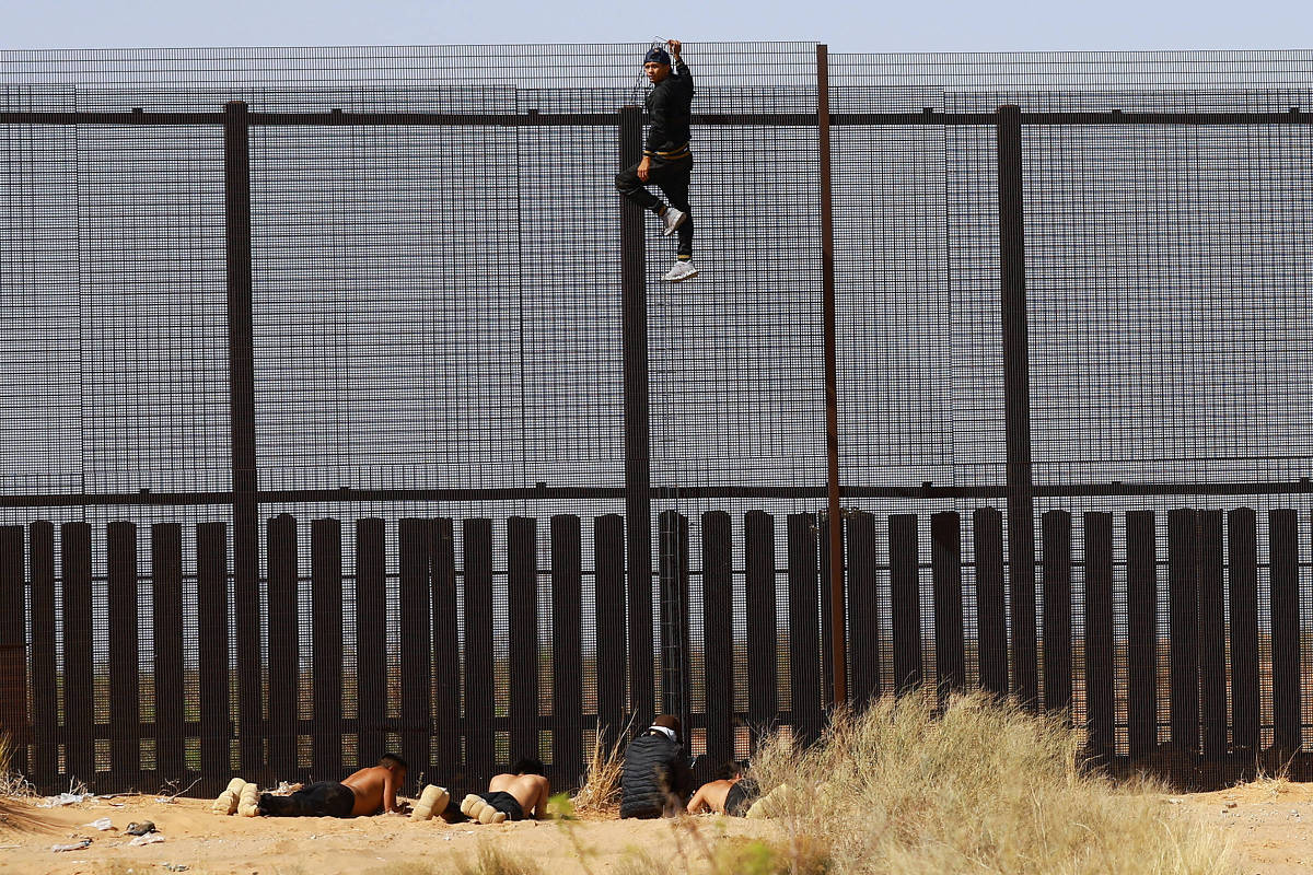 Jovem tenta pular cerca na fronteira entre México e EUA em Ciudad Juarez na última terça-feira (29) (Foto: Stringer/Reuters)