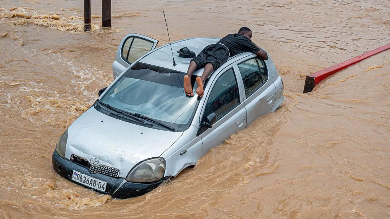 Este homem se agarrou ao teto de um carro no bairro N'djili da cidade (Foto: AFP)