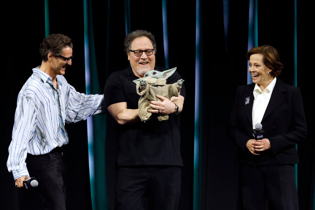 De esquerda a direita, o ator Pedro Pascal, o diretor Jon Favreau (com o boneco de Grogu) e a atriz Sigourney Weaver apresentam 'The Mandalorian e Grogu' na Star Wars Celebration de Japão. (Foto: FRANCK ROBICHON/EFE)