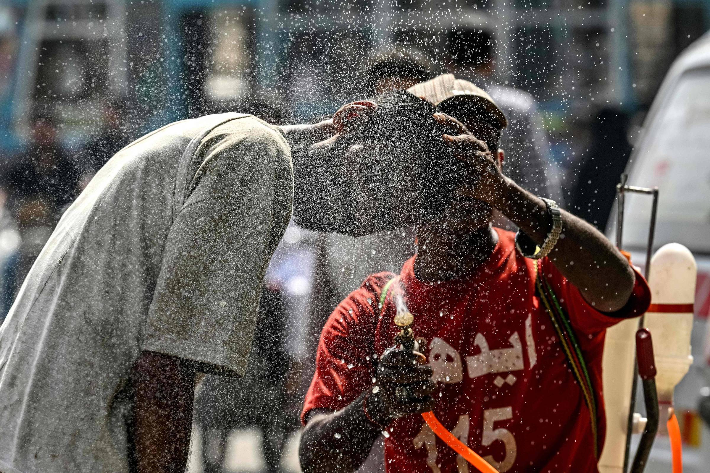 Moradores de Carachi, no Paquistão, usam jato de água para aliviar calor (Foto: Asif Hassan/AFP)