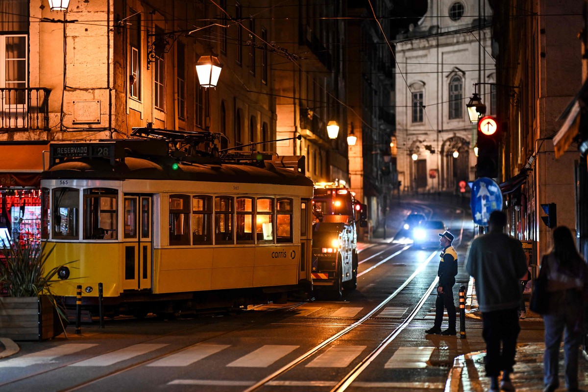 Policial observa bonde elétrico ser rebocado no centro de Lisboa após o fim do apagão (Foto: Patricia de Melo Moreira/AFP)