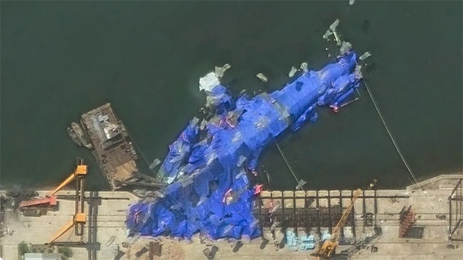 O destróier agora está deitado de lado coberto por grandes lonas azuis, mostram imagens de satélite. (Foto: Maxar)