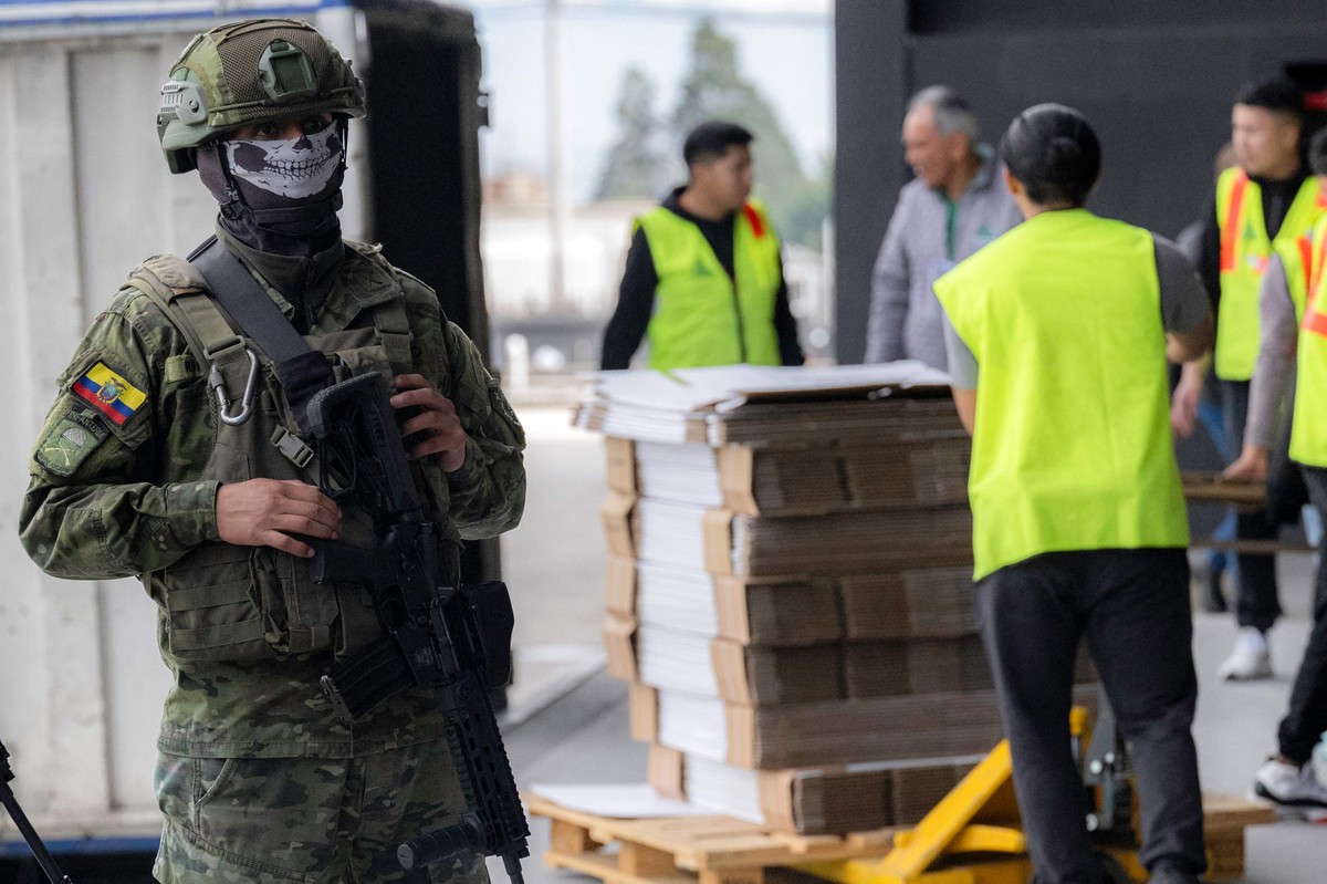 Soldado equatoriano monitora o trabalho de integrantes do Conselho Nacional Eleitoral em Quito (Foto: Luis ACOSTA / AFP)
