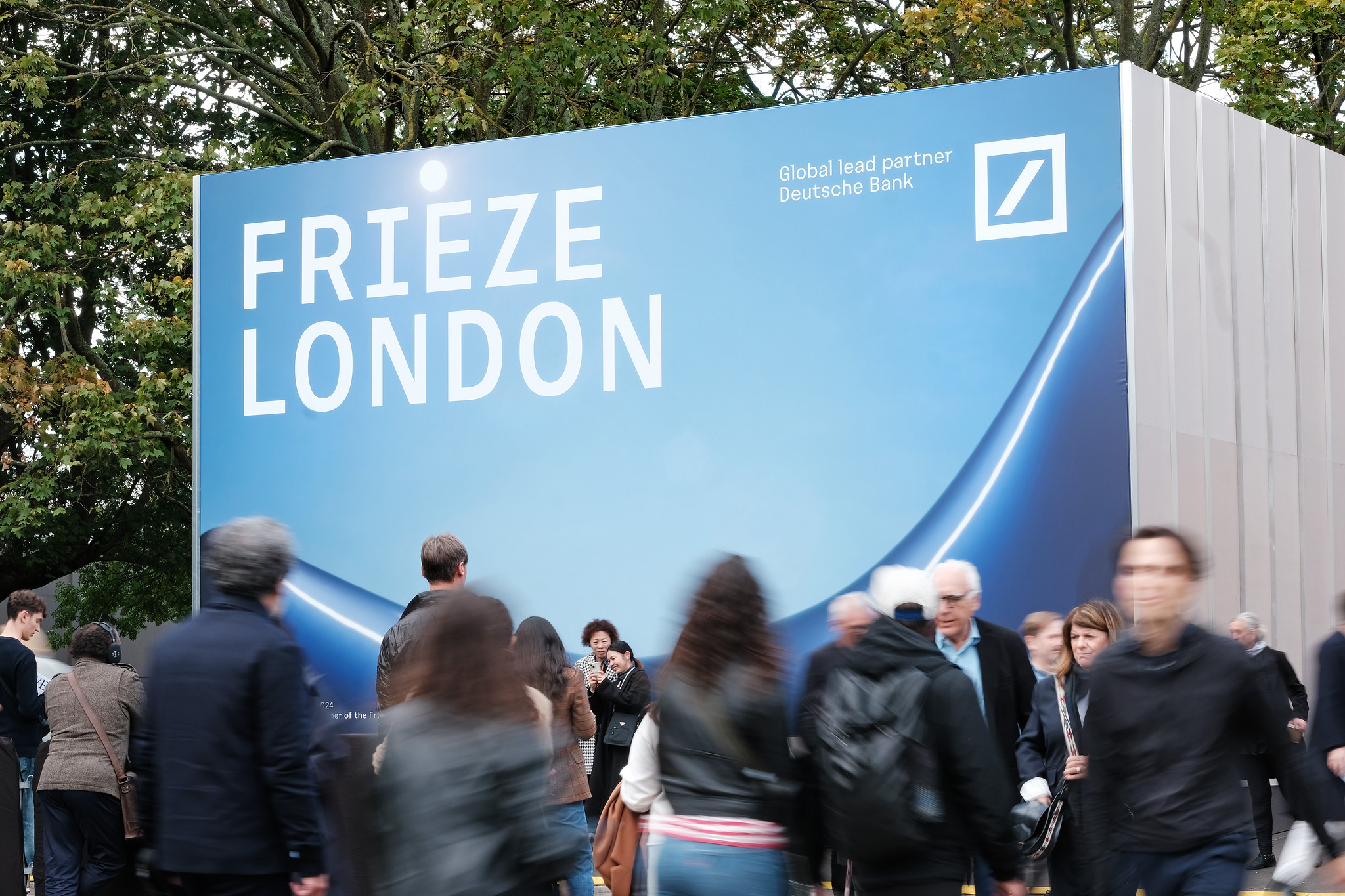 Feirantes caminham em frente ao letreiro da edição de 2024 da Frieze London. (Foto: Linda Nylind/Courtesy of Frieze)