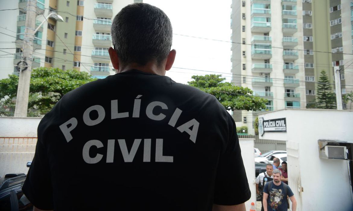 Policiais civis saem de prédio com carro material apreendido em operação contra banqueiros (Foto: Reprodução/TV Globo)