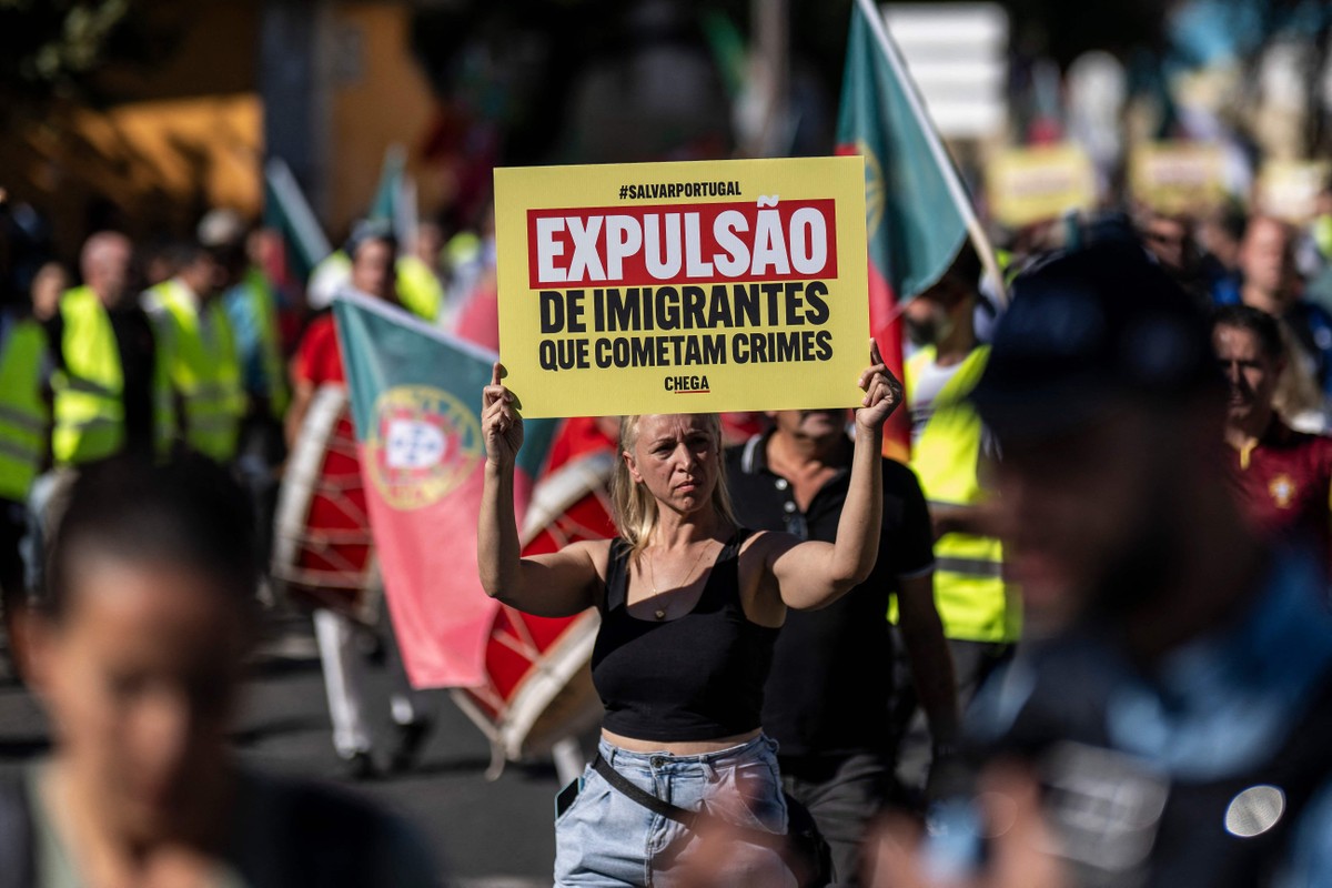 Partidária do Chega, de ultradireita, mostra cartaz durante uma manifestação em Lisboa contra imigração. (Foto: Patrícia de Melo Moreira/AFP)