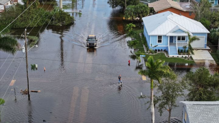 Uma pessoa caminha por águas de inundação que alagaram um bairro após a passagem do furacão Milton em 10 de outubro de 2024, em Punta Gorda, Flórida. A tempestade atingiu a costa como um furacão de Categoria 3 na área de Siesta Key, causando danos e inundações em toda a Flórida Central. (Foto: Joe Raedle/Getty Images)