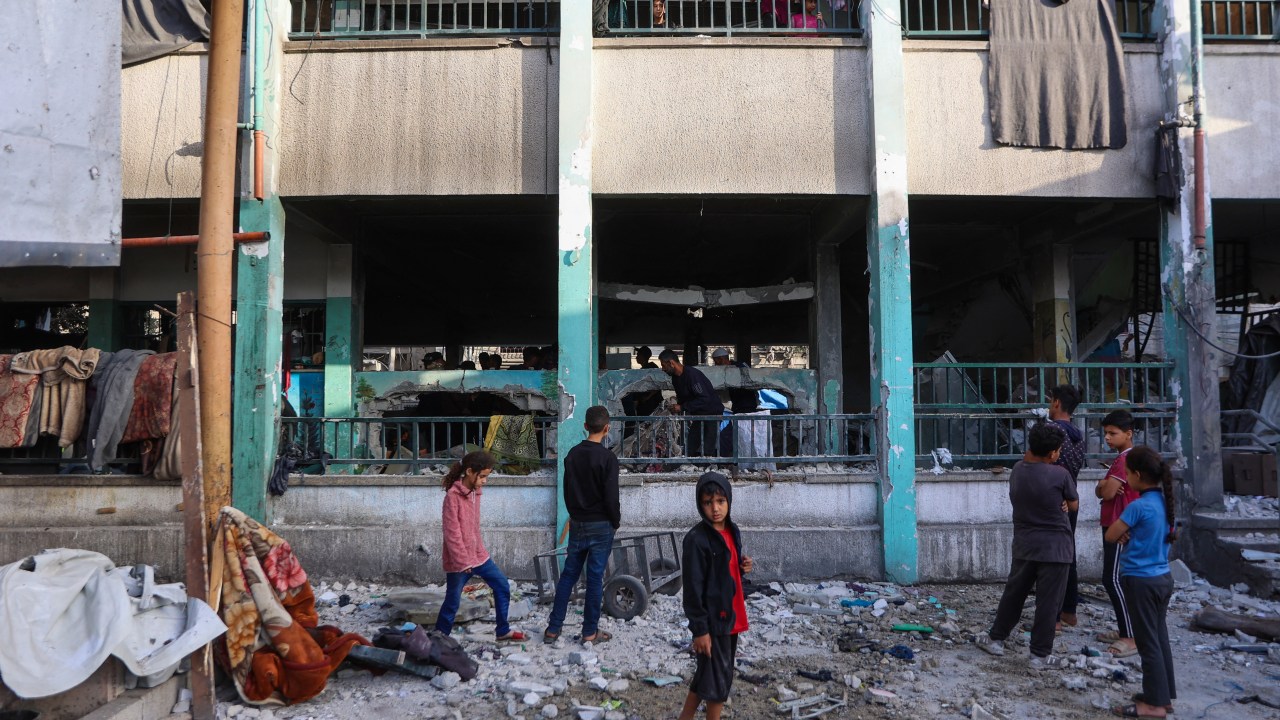 Crianças observam destroços da escola Fahmi Al-Jarjawi, em Gaza, atingida por ataques israelenses. 26/5/2025. (Foto: Omar AL-QATTAA/AFP)