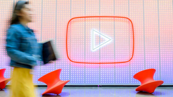 Pessoas passam pelo logotipo do YouTube enquanto o Google celebra o 20º aniversário do primeiro vídeo enviado ao YouTube, na sede da empresa em San Bruno, Califórnia, em 23 de abril de 2025. (Foto: Josh Edelson | AFP | Getty Images)