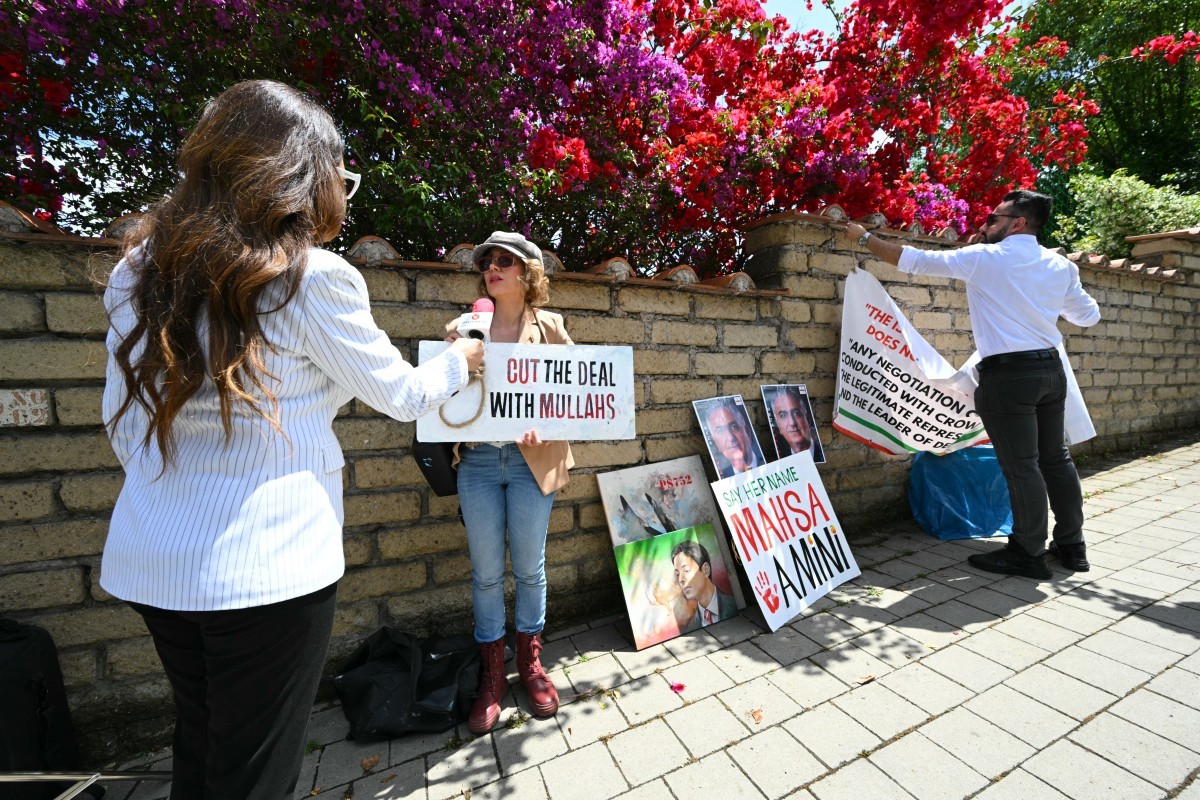 Manifestantes iranianos seguram cartazes do lado de fora da embaixada de Omã, que sedia a quinta rodada de negociações nucleares entre o Irã e os Estados Unidos. (Foto: Andreas SOLARO / AFP)