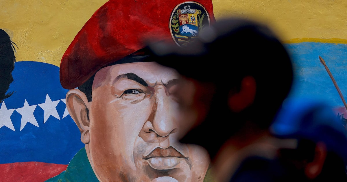Um homem passa por um mural com a imagem de Hugo Chávez durante um comício para comemorar os resultados oficiais das últimas eleições regionais, em 31 de maio de 2025. (Foto: Pedro Mattey/AFP)