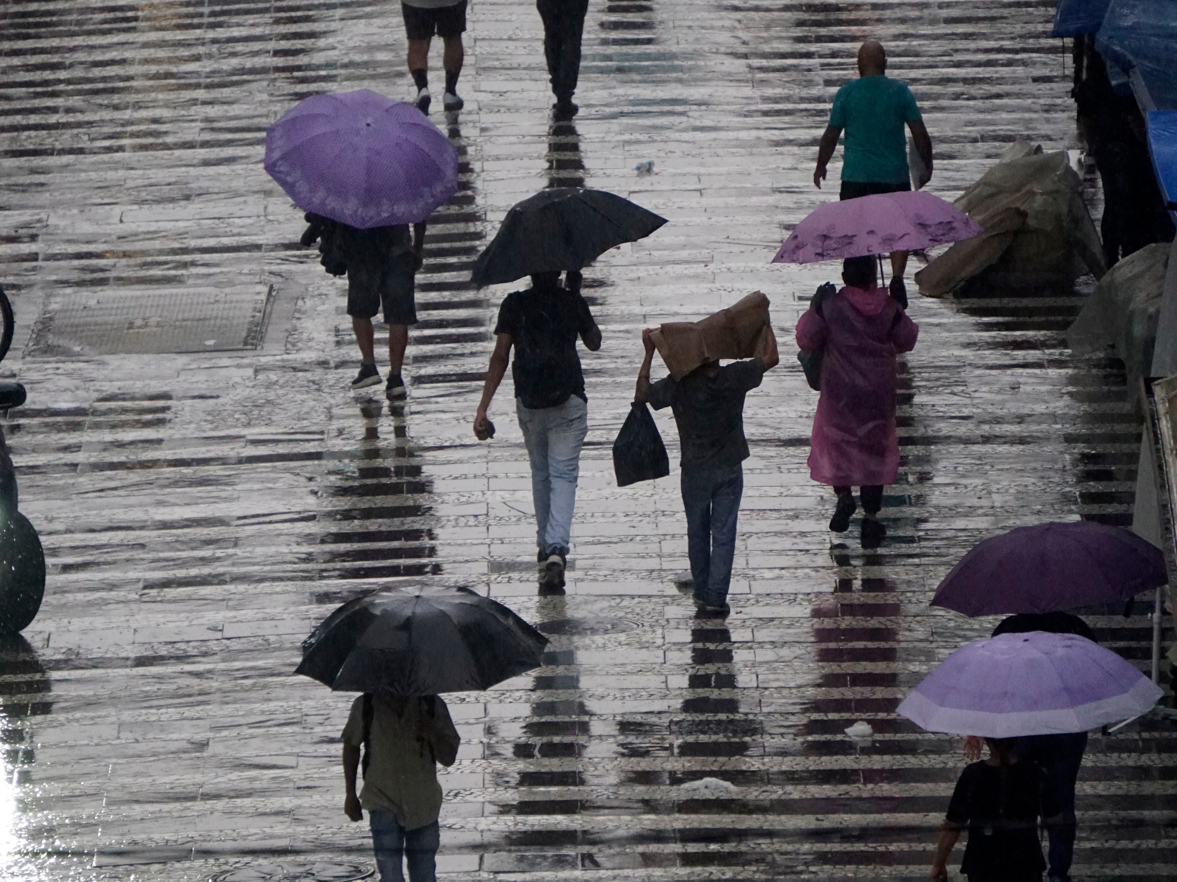 Pedestres se protegem da chuva na região central da cidade de São Paulo (Foto: CRIS FAGA - 18.mar.25/ESTADÃO CONTEÚDO)