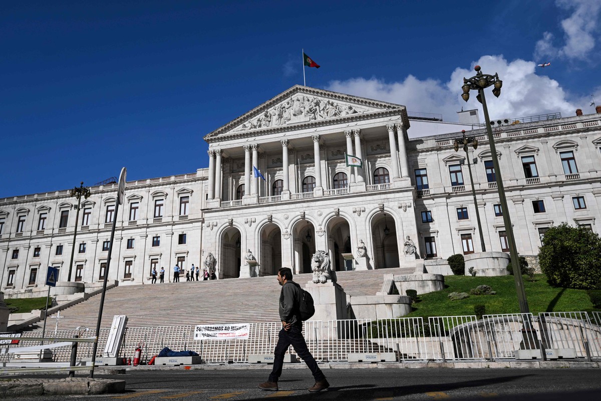 Pedestre caminha diante do Parlamento de Portugal: mudança depende dos deputados (Foto: Patrícia de Melo Moreira/AFP)