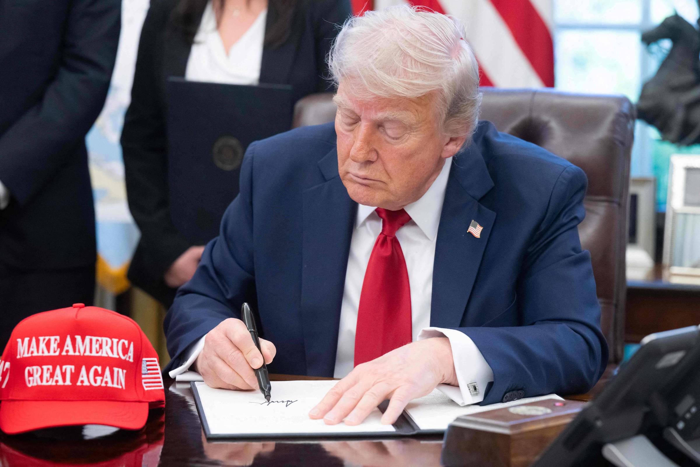 O presidente dos EUA, Donald Trump, assina decretos no Salão Oval da Casa Branca em Washington. (Foto: Saul Loeb/AFP)