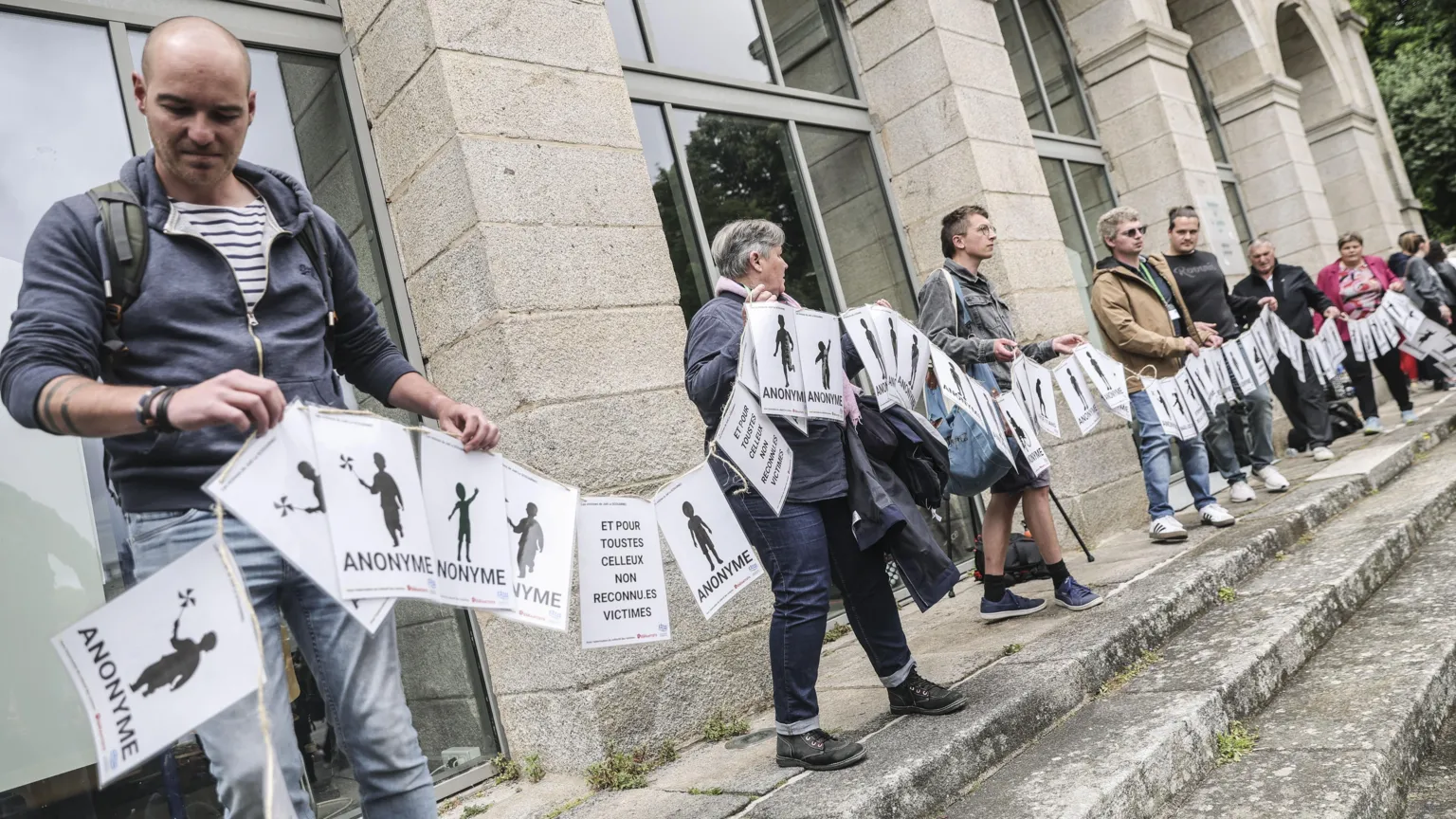 Uma faixa composta por centenas de folhas de papel para representar as vítimas de Le Scouarnec foi estendida perto do tribunal em Vannes na quarta-feira. (Foto: EPA)