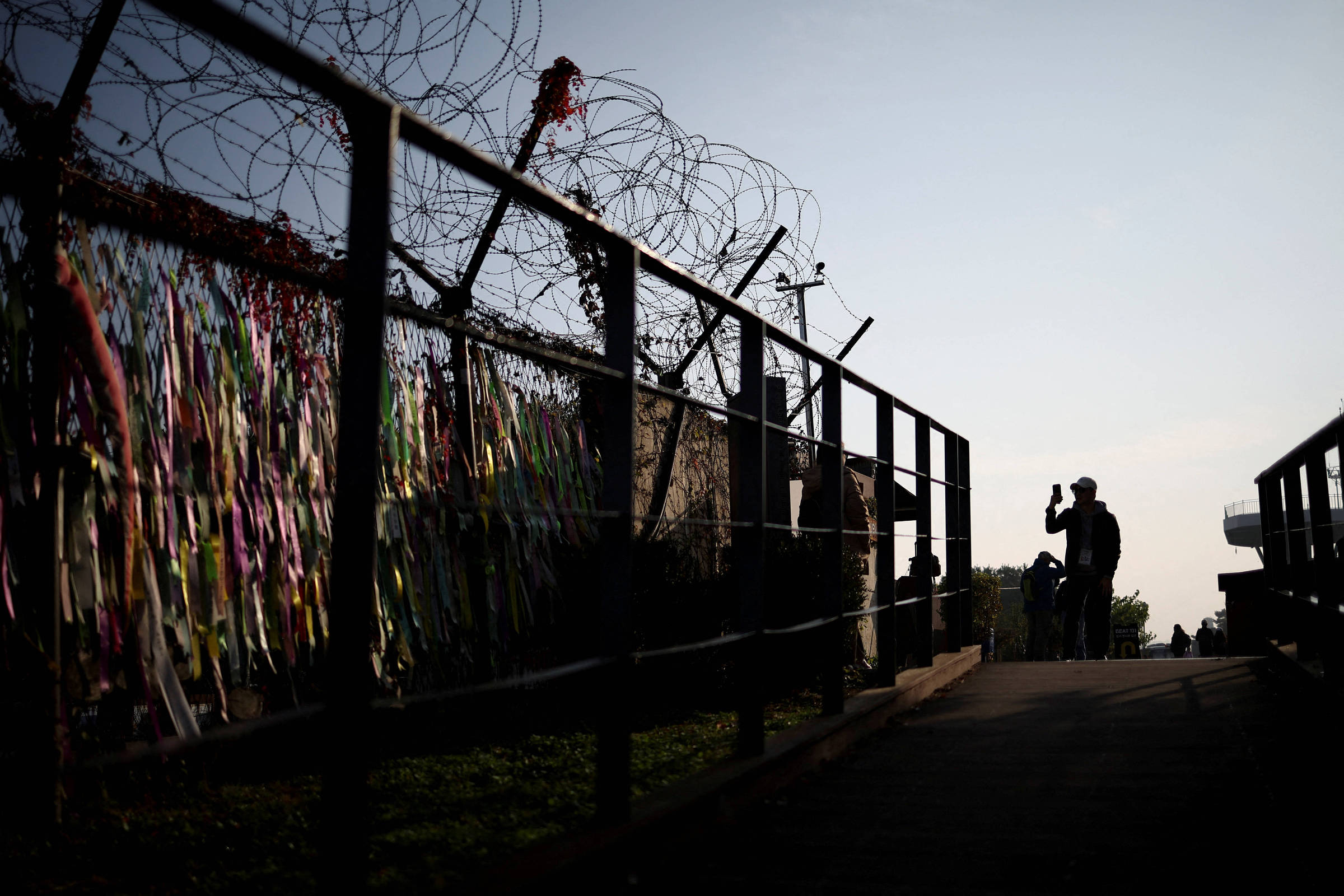 Pessoa tira fotos em frente a uma cerca militar próxima à zona que separa as duas Coreias, em Paju. (Foto: Kim Hong-Ji/Reuters)