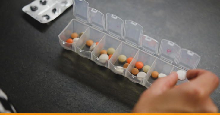 pessoa segurando um comprimido para colocar em uma caixinha de remédios