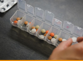 pessoa segurando um comprimido para colocar em uma caixinha de remédios