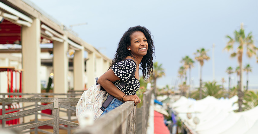 Mulher debruçada sobre um para-peito em uma casa praiana. 
