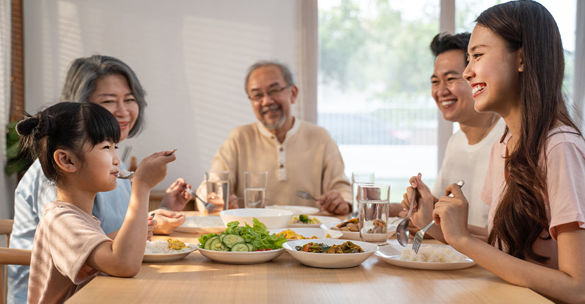Família asiática comendo ao redor da mesa. Avós, pai, mãe e filha.
