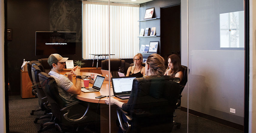 Quatro pessoas ao redor de uma mesa fazendo uma reunião