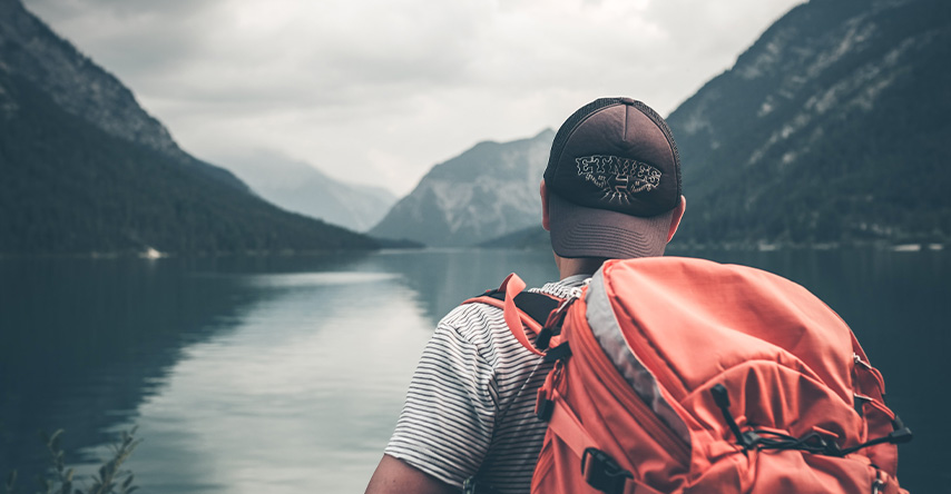 Homem viajando por um lago entre montanhas.