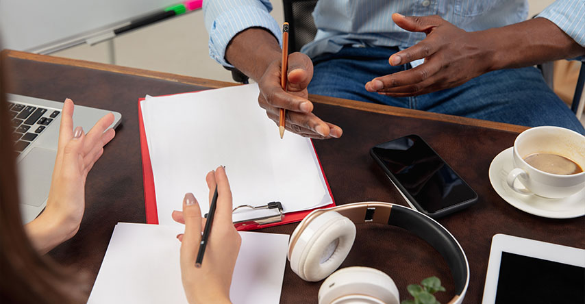 Homem e mulher conversando, a imagem mostra suas mãos sobre uma mesa.