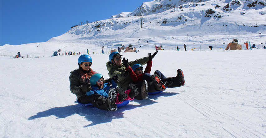Família escorregando na neve em estação de esqui Farellones, no Chile