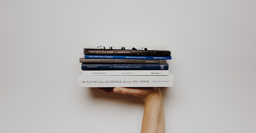 Uma mão segurando vários livros empilhados