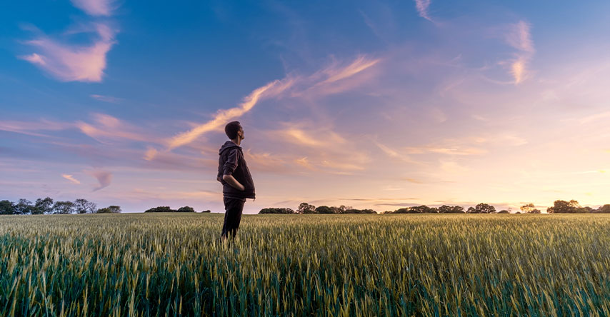 Homem em um campo gramado olhando para o céu.