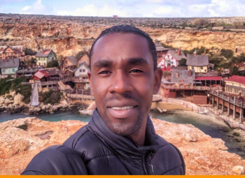 Homem em frente a vila do Popeye, em Malta