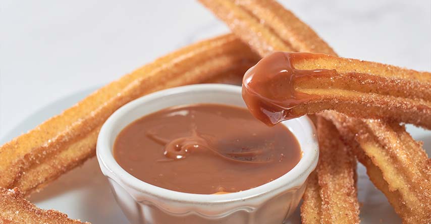 Churros e um pote com chocolate derretido