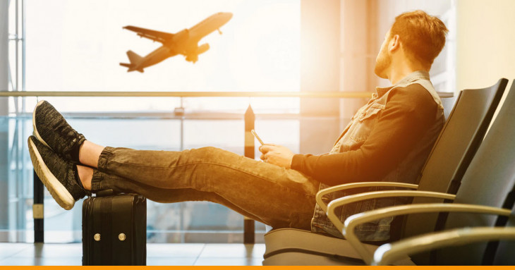 homem sentado no banco de um aeroporto olhando a paisagem