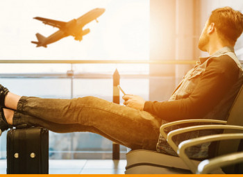 homem sentado no banco de um aeroporto olhando a paisagem