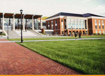 Imagem panorâmica de uma escola, com alunos andando na calçada