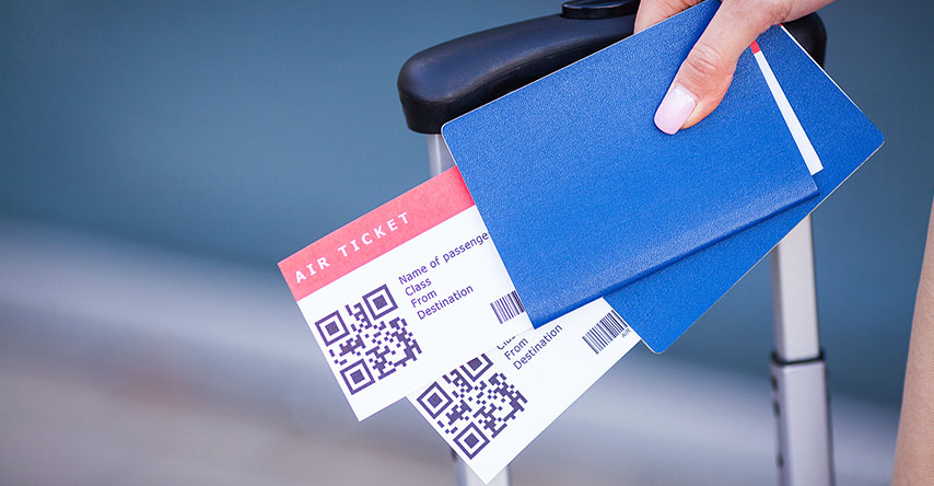Mulher segurando com uma mão, a mala, o passaporte e os tickets aéreos