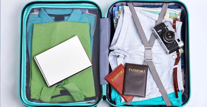 Mala aberta, em seu interior contém roupas, um caderno e dois passaportes