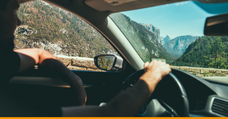 pessoa dirigindo um carro e a paisagem montanhosa ao fundo