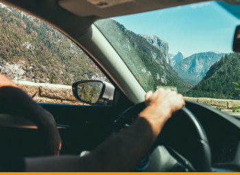 pessoa dirigindo um carro e a paisagem montanhosa ao fundo
