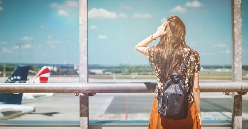 mulher com mochila olhando para dentro de um aeroporto