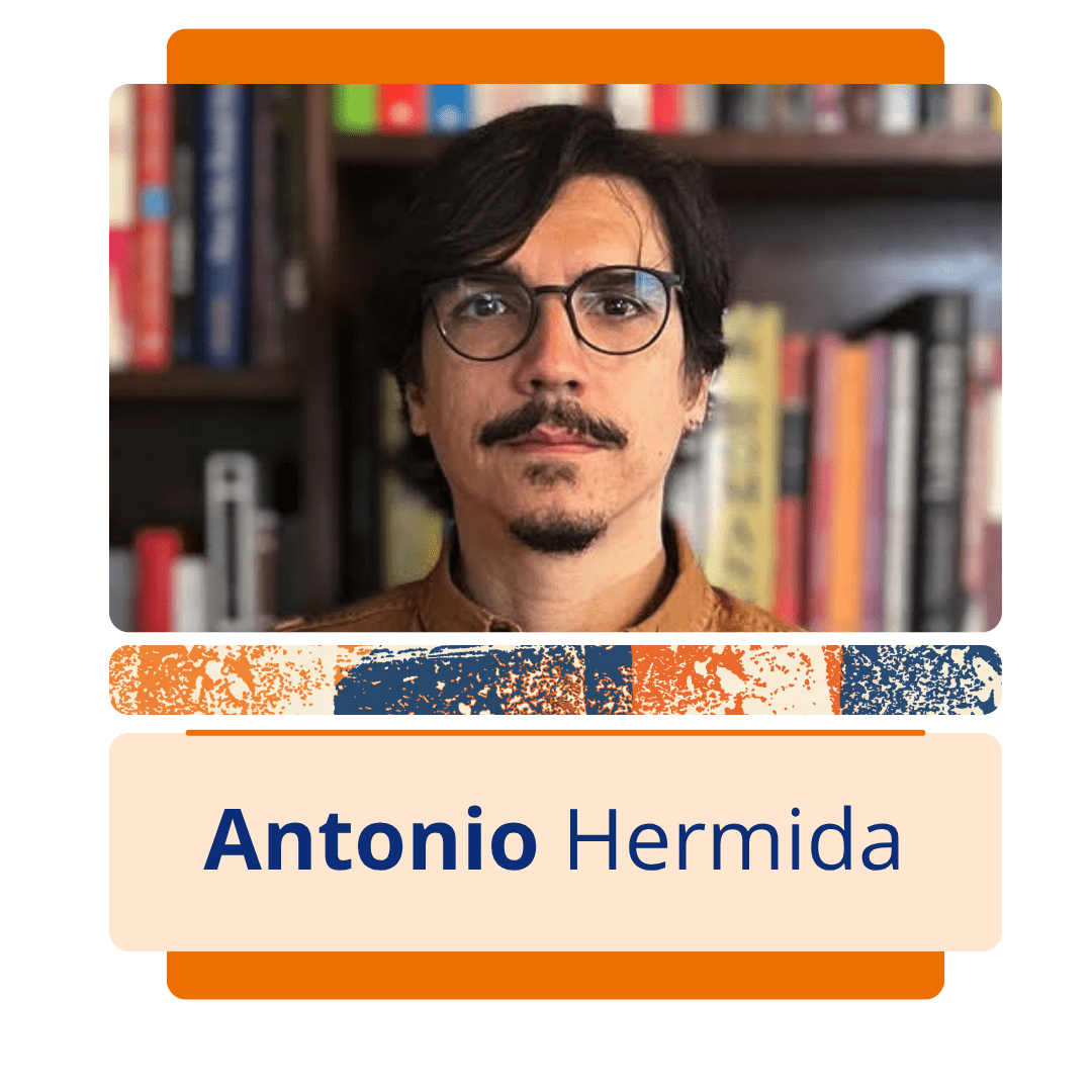 Card vertical com fundo branco e uma moldura central de bordas arredondadas em tons de laranja. Na metade superior da moldura, h&aacute; uma foto colorida de Antonio Hermida, um homem branco de cabelos pretos, lisos e jogados para o lado esquerdo. Ele tem bigode e cavanhaque pretos, usa &oacute;culos de grau redondos com arma&ccedil;&atilde;o escura e veste uma camisa de bot&atilde;o na cor mostarda ou marrom claro. Ao fundo, h&aacute; uma estante repleta de livros coloridos desfocados. Logo abaixo da foto, uma faixa estreita com textura abstrata em azul, laranja e branco separa a imagem da metade inferior do card, onde h&aacute; um ret&acirc;ngulo bege com o nome 