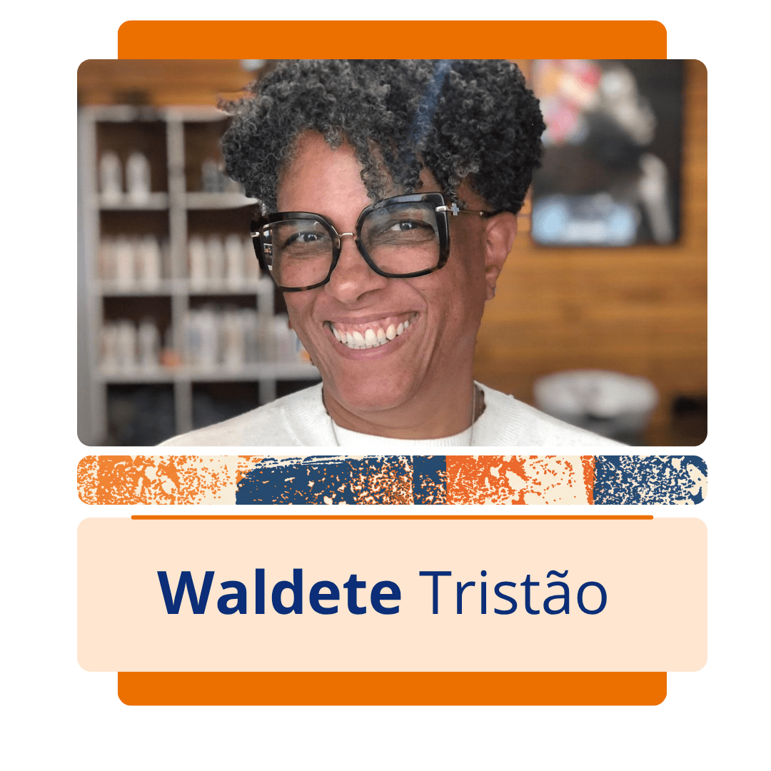 Card vertical com fundo branco e uma moldura central de bordas arredondadas em tons de laranja. Na metade superior da moldura, h&aacute; uma foto colorida da educadora e escritora Waldete Trist&atilde;o, uma mulher negra de pele clara com cabelos crespos, curtos e grisalhos. Ela sorri abertamente para a frente, mostrando os dentes, usa &oacute;culos de grau grandes com arma&ccedil;&atilde;o escura e veste uma blusa branca de gola alta. Ao fundo, h&aacute; um ambiente interno desfocado com paredes de madeira e uma estante com produtos. Logo abaixo da imagem, uma faixa estreita com textura abstrata em azul, laranja e branco separa a foto da metade inferior do card, onde h&aacute; um ret&acirc;ngulo bege com o nome 