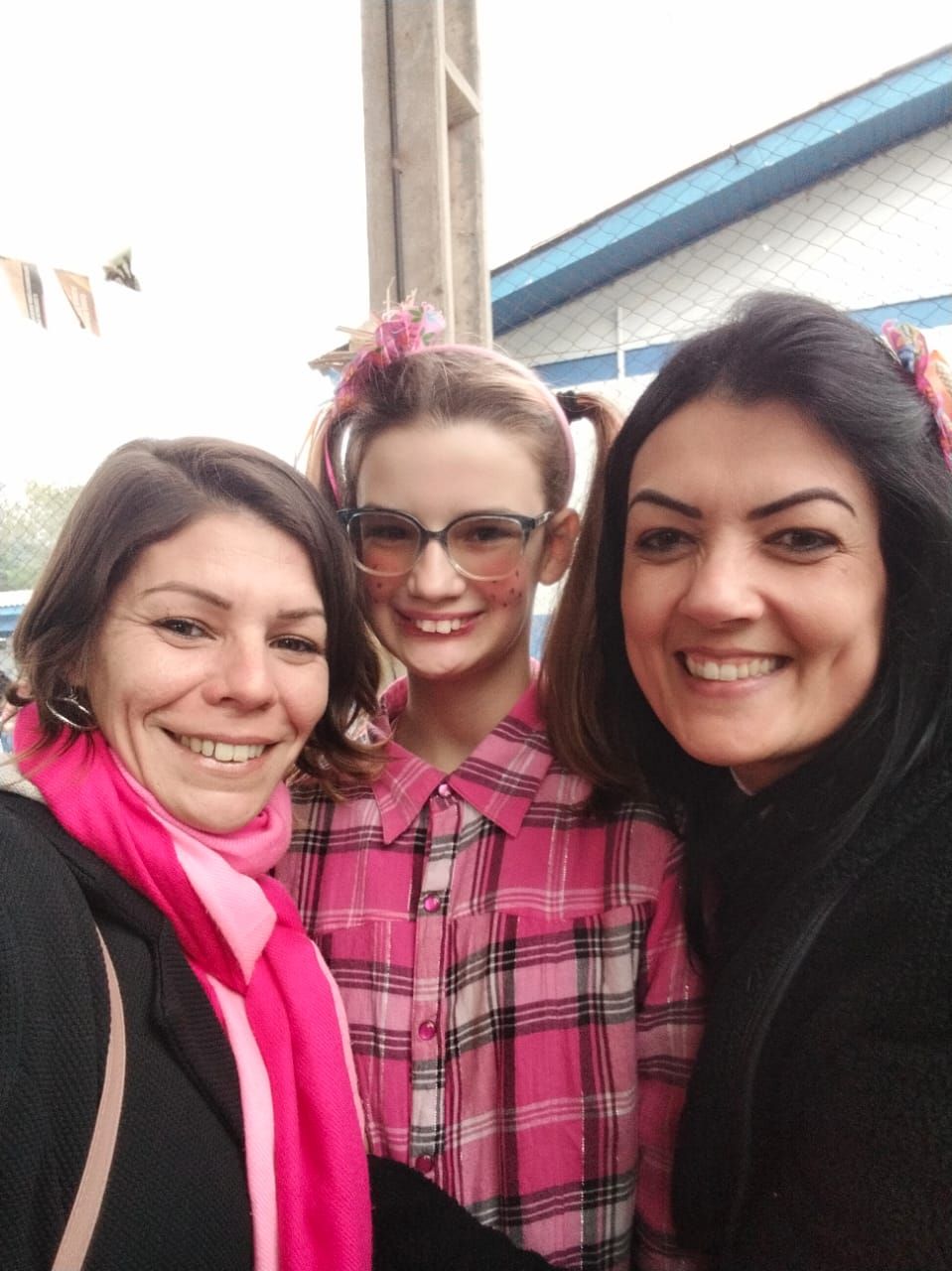 Da esquerda para direita est&aacute; posicionada a estudante de pedag&oacute;gia Thais Brum, sua filha com roupa xadrez rosa e a professora da crian&ccedil;a 