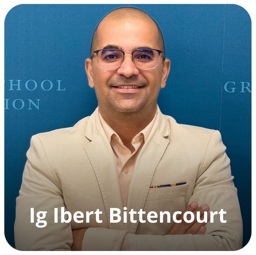 Um homem branco, sem cabelos. Ele usa &oacute;culos e uma roupa com tons de rosa claro. 