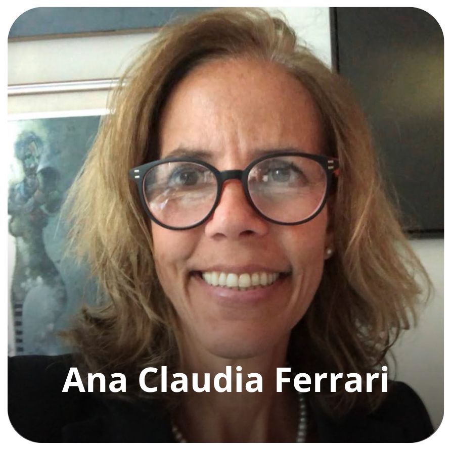 Uma mulher, de cabelos em tons de marrom e loiro, na altura dos ombros. Ela usa um &oacute;culos preto, blazer preto e um colar de p&eacute;rolas 