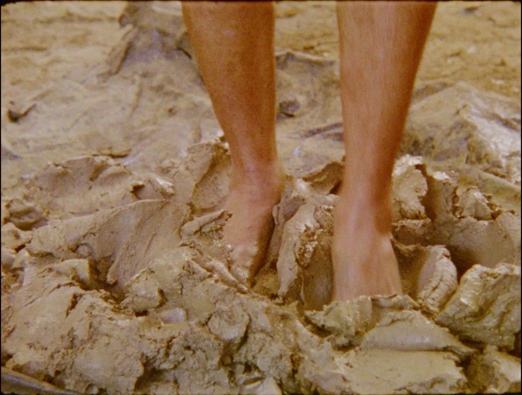 Na imagem, pés estão amassando barro.