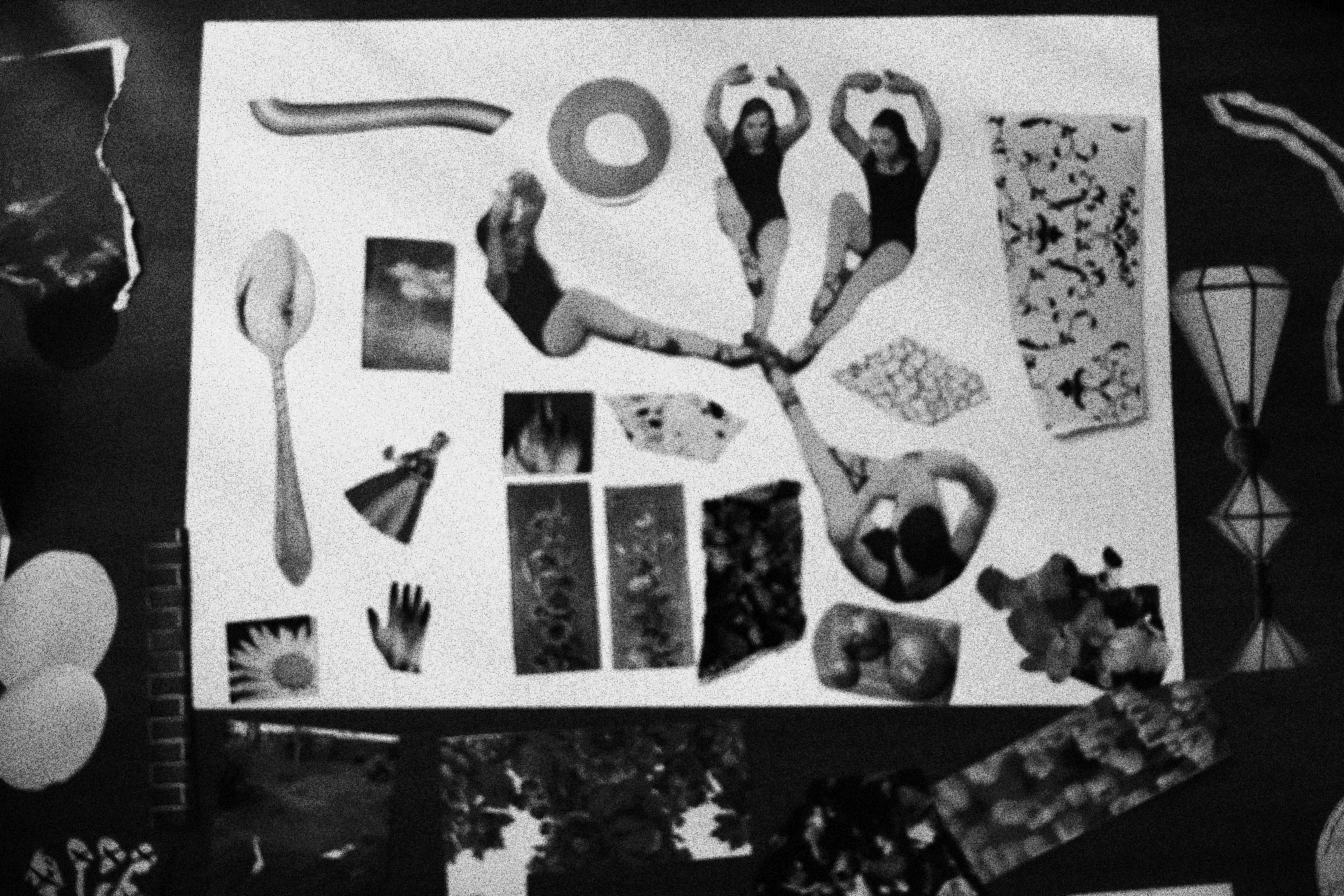 Uma foto em preto e branco de uma colagem de recortes sobre uma superfície branca. Os elementos estão dispostos de forma organizada. Incluem três recortes de mulheres em poses de dança ou ginástica, um recorte de uma colher, uma mão, um girassol, uma ampulheta e vários padrões abstratos.